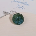 Macro shot of green and blue swirl glass bead pendant with textured dimpled surface - Dark Green