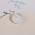 Macro shot of clear textured glass sphere pendant with hammer pattern and integrated loop - White