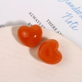 Vista macro di ciondoli a cuore in resina arancione su un piatto di ceramica bianca - Stile Cuore Arancione Jelly