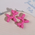 Detail van roze acryl ballonhond bedeltjes op keramische schaal voor sieraden - Rozerood