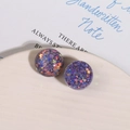 Detalle de pendientes de resina violeta con purpurina colorida en plato cerámico - Morado
