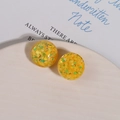 Detalle de pendientes de resina amarilla con lentejuelas de colores en bandeja de cerámica - Amarillo