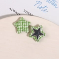 Macro view of star-shaped fabric patch with green weave and metallic star detail - Green