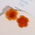 Detailansicht von orangefarbenen, mattierten Harz-Sonnenblumenanhängern auf Weißkeramik - Dunkelorange