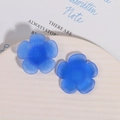 Macro shot of matte dark blue resin flower charms with textured centers on white plate - Blue