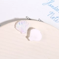 Dettaglio macro di ciondoli in resina a forma di conchiglia iridescente e bianco opaco - Bianco