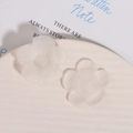 Macro detail of matte frosted resin flower charms with smooth edges and translucent white finish - White