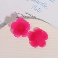Close-up of matte magenta resin flower charms with radial texture on white ceramic plate - Rose Red