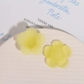 Macro view of matte yellow flower resin charms on a white textured ceramic dish - Yellow