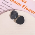 Macro shot of dark grey irregular resin charms for DIY earrings on a ceramic plate - Gray
