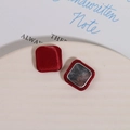 Detailed view of square burgundy silk fabric buttons with elegant metallic backing on tray - Red