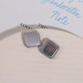 Close-up of grey fabric square magnetic buttons with twill texture on a ceramic tray - Silver