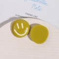 Vista macro di ciondoli sorridenti in resina giallo senape su vassoio decorativo - Verde