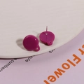 Detailed view of dark purple resin round earrings with silver studs on a white plate - Purple