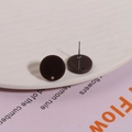 Nahaufnahme dunkelbrauner runder Harz-Ohrstecker mit kleinem Loch für DIY-Schmuckherstellung - Braun