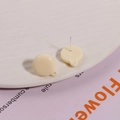 Macro shot of cream resin round stud earring with metal pin and hanging hole detail - White