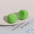 Detail of glossy lime green resin spherical studs on a white textured ceramic dish - Green