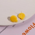 Detail of bright yellow round resin earrings with small hole on a white tray - Yellow
