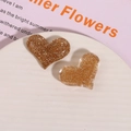 Dettaglio di accessori per capelli a cuore con glitter in resina marrone - Oro Uno