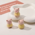 Vista dettagliata di tre graziose statuine di maialini rosa in abiti gialli lavorati - Stile Maialino Rosa