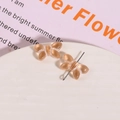 Close-up of translucent amber glass bow jewelry components on a white display tray - Orange with White Thread