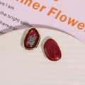 Detail of red resin oval earrings with gold edges and dried flowers in a ceramic dish - Blue Dried Flower