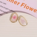 Detailed macro view of oval gold alloy earrings with pink dried flowers and pearls - Pink Flower