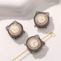 Nahaufnahme einer grauen Wecker-Perle mit Straß und Goldzeigern für DIY-Schmuckherstellung - 1 Stück / Schwarz und Grau