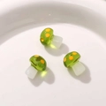 Macro detail of three semi-transparent resin mushroom charms with green dots for DIY jewelry - Green