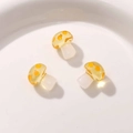 Macro shot of three cute translucent yellow resin mushroom charms with orange dots - Yellow