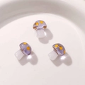 Close-up of three purple resin mushrooms with yellow dots and white translucent stems - Grey Purple