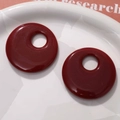 Close-up of 50mm dark red hollow resin geometric round pendants for DIY jewelry crafts - Red