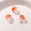 Macro shot of three glossy resin mushroom charms with red dotted caps for DIY jewelry - Orange
