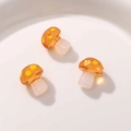 Close-up of three orange resin mushroom charms with yellow polka dots for DIY jewelry - Turmeric