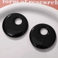 Close-up of 50mm black hollow circular resin charms for DIY earrings and jewelry making - Black