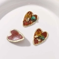 Detail of handmade resin heart pendants with dried flowers and gold foil elements - Brown