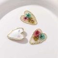 Vue macro détaillée de breloques en résine en forme de cœur avec fleurs séchées et métal - Blanc