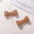 Close-up of resin bow charms with colorful dots and pre-drilled holes for DIY jewelry - Brown