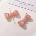 Vue macro de breloques nœuds en résine rose à pois colorés pour accessoires de cheveux - Rose