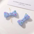 Detail of light blue resin bow charm with colorful polka dots for DIY jewelry crafts - Blue