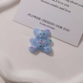 Dettaglio di un ciondolo a forma di orso in resina blu chiaro con pois colorati per DIY - Blu