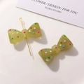 Close-up of olive green resin bow charm with colorful dots and a gold DIY metal pin - Grass Green