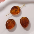 Macro view of amber droplet-shaped resin beads with internal smoke swirl and hole detail - 1 Piece / Amber