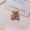 Dettaglio di un ciondolo orso in resina marrone lucido con pois colorati su vassoio - Marrone