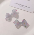 Detailed view of two cute translucent resin bow charms with colorful polka dots - Blue