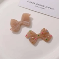 Detail of resin bow accessories with marble texture and colorful polka dot patterns - Brown
