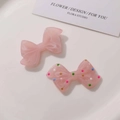 Detailed view of pink resin bow charms with marble texture and colorful polka dots design - Semi-transparent Pink