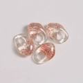 Macro shot of four asymmetric resin charms with embedded pink dried flowers for DIY jewelry - Pink