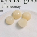 Vista macro de cuatro cuentas redondas de resina crema de 16 mm para joyas DIY - Beige