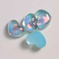 Detalle macro de cuentas de resina de corazón iridiscente para joyería artesanal - Azul